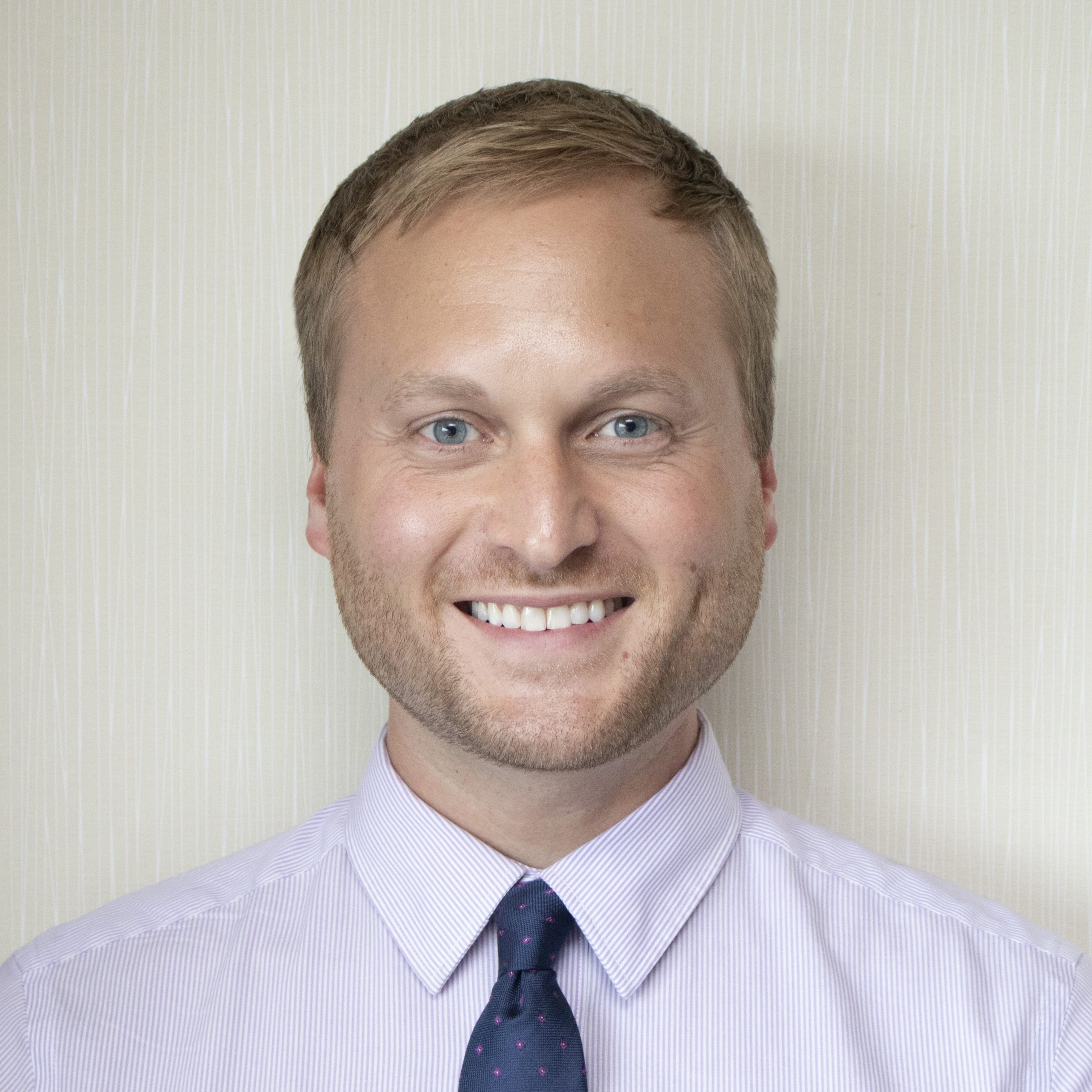 Shane Redman headshot Studio portrait of a person in a dress shirt and tie on a light background