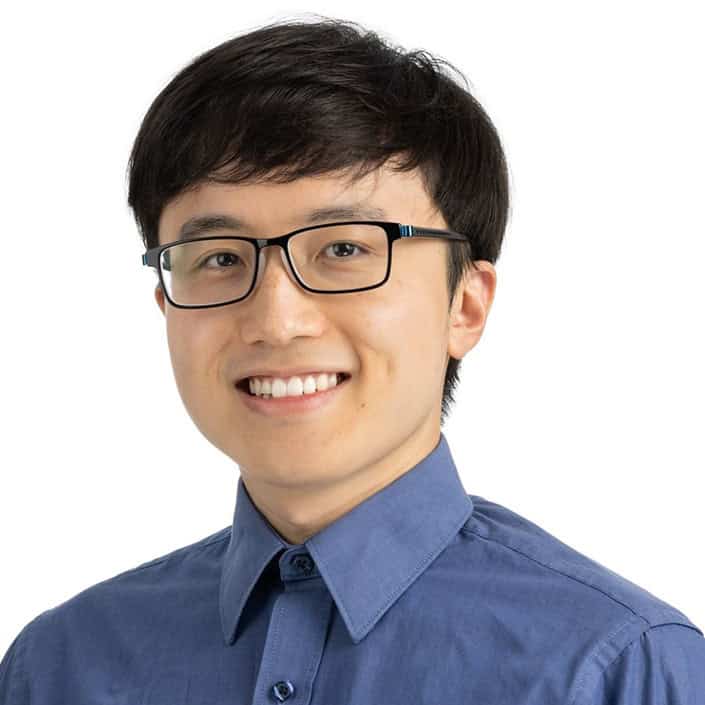 man smiling at camera. wearing glasses and a blue shirt