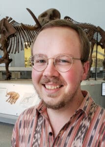 Willam Weaver smiling at camera wearing glasses and a plaid shirt