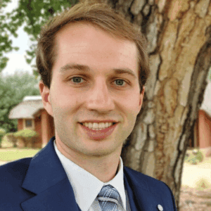 Seth Temple headshot smiling at the camera wearing a suit