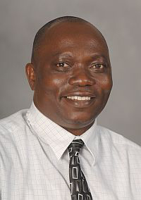 Studio headshot of a man in a suit and tie against a light background