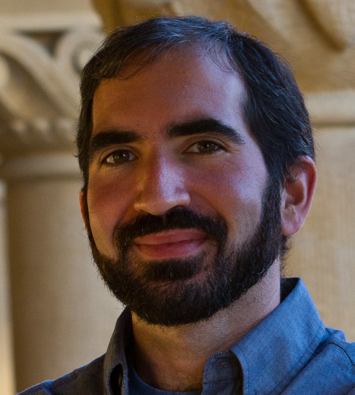 Side-profile portrait of a man in a blue shirt against a neutral background