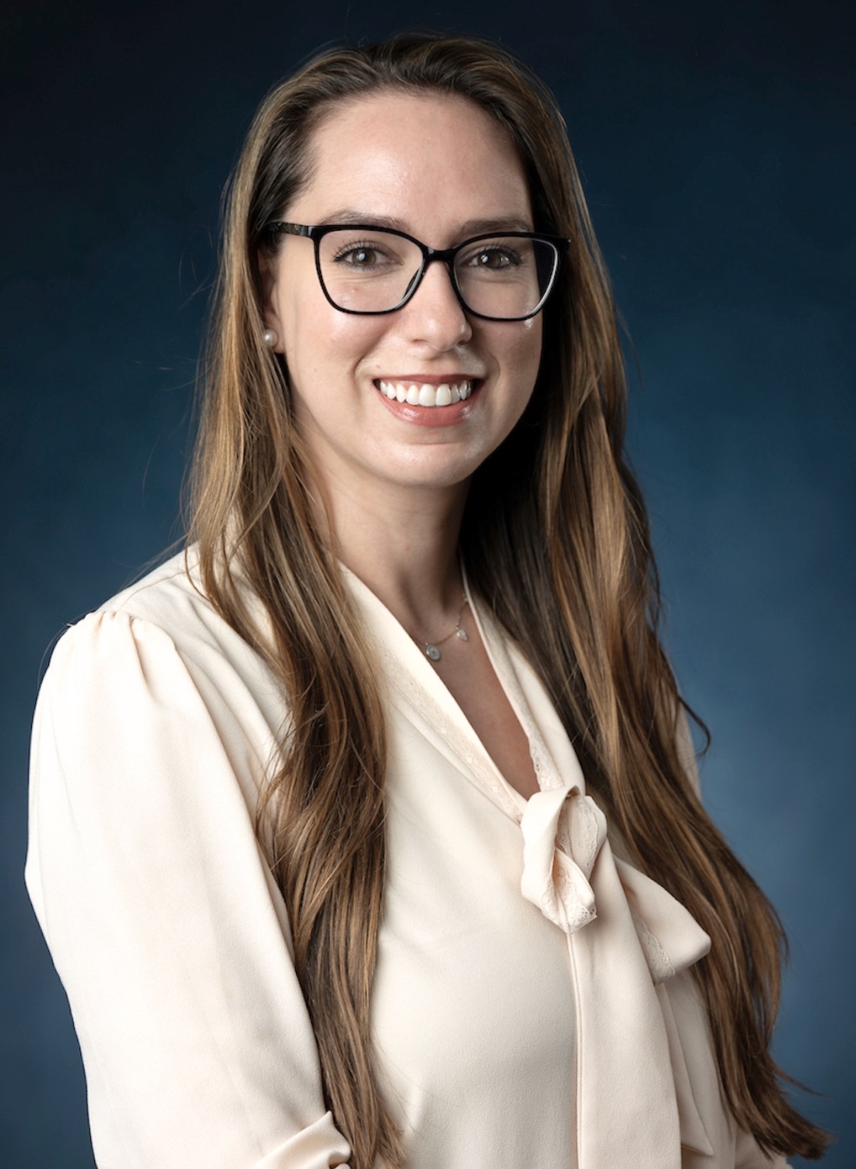 Studio portrait of a person with long hair in a white blazer against a white background