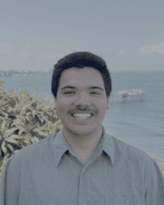 Man smiling at camera, ocean in background.