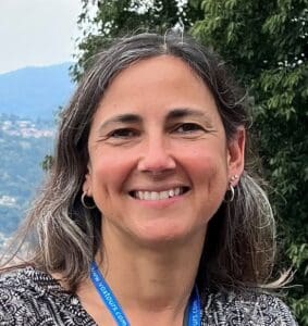 Outdoor portrait of a woman with long hair wearing a lanyard, with trees behind