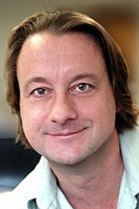 Close-up portrait of a man with short hair against a light background