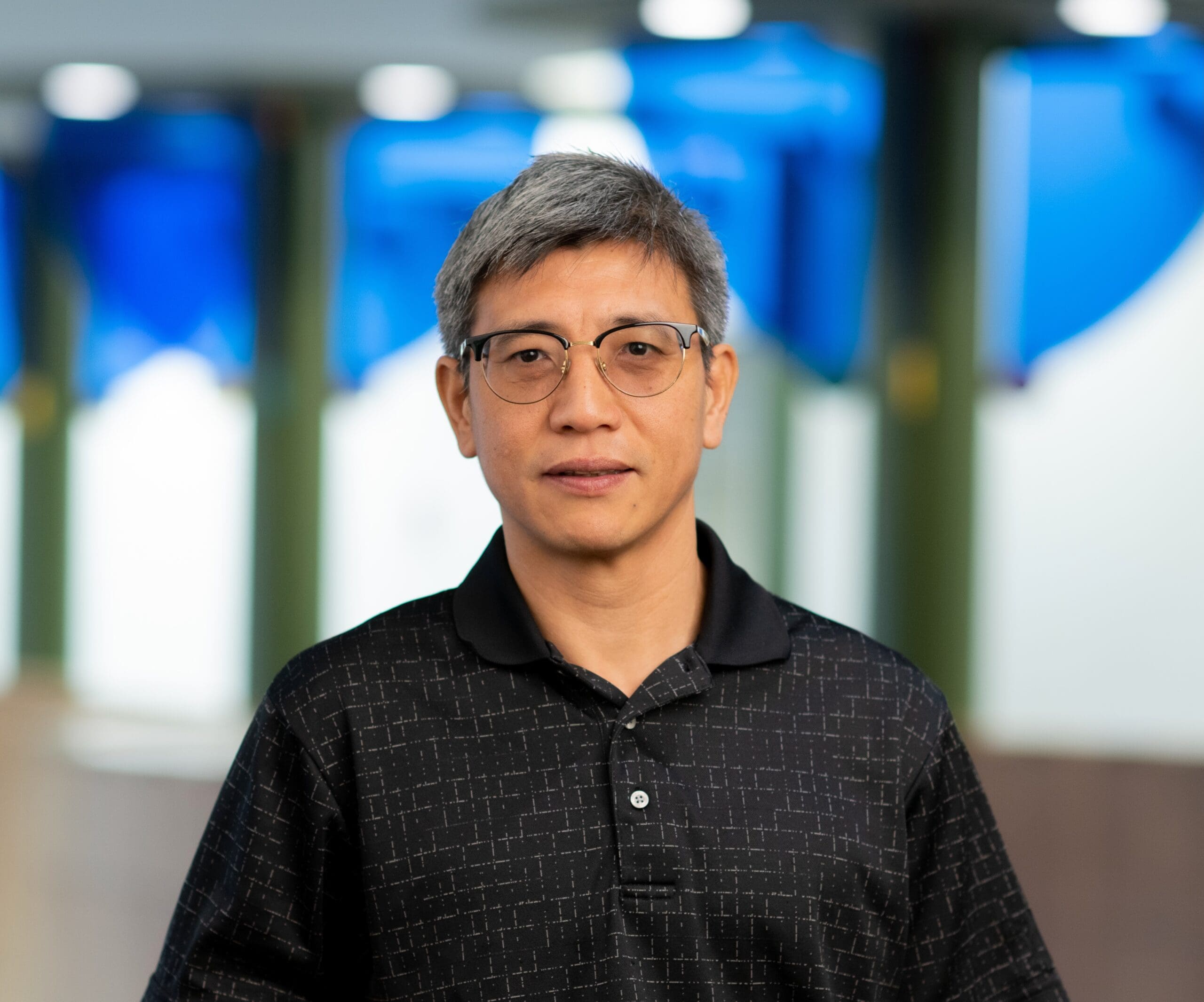 Indoor portrait of a person in a dark patterned shirt with a blurred office background