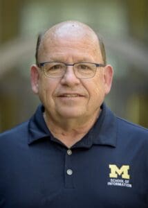 Outdoor portrait of a person in a navy shirt with the School of Information on it.