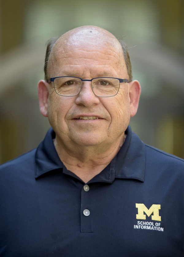 Outdoor portrait of a person in a navy shirt with the School of Information on it.