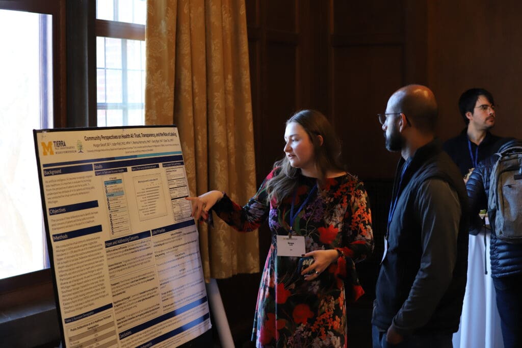 A person standing in front of their poster presenting to an onlooker