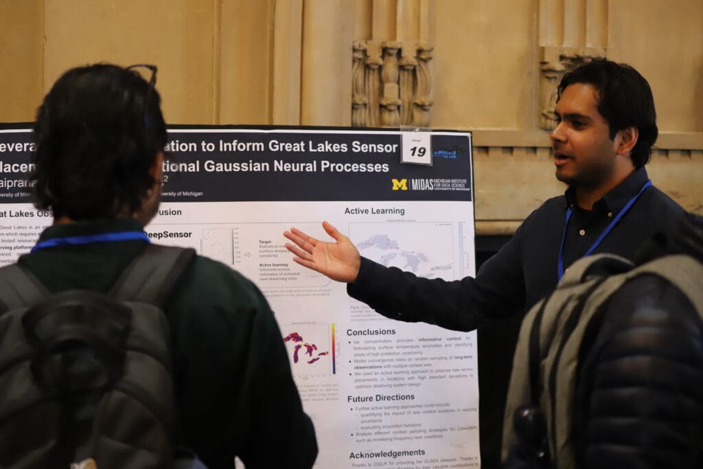 A person standing in front of their poster presenting to an onlooker