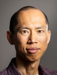 Man looking into the camera with a half smile.